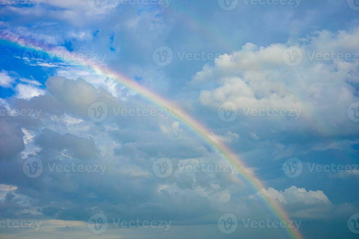 hermosa multicolor arco iris después lluvia en azul cielo y blanco nubes en el medio de un pueblo en un comunidad en Tailandia foto