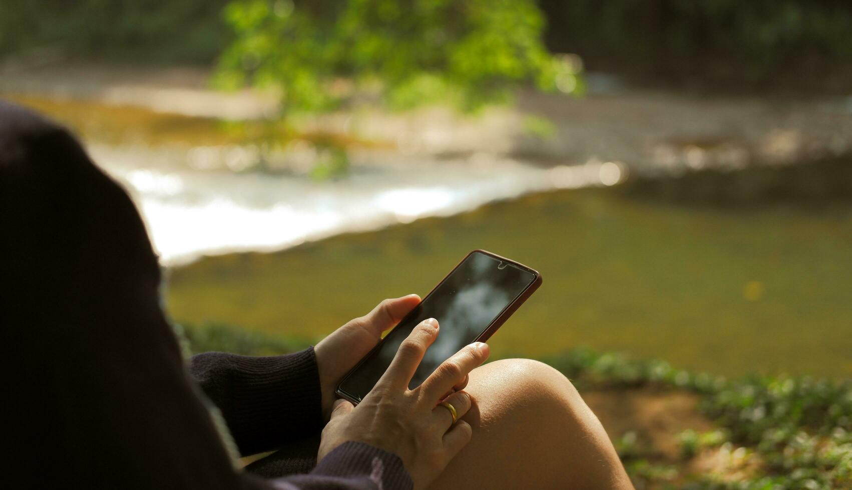 Woman relaxing with mobile phone in garden Suitable for making infographics. photo