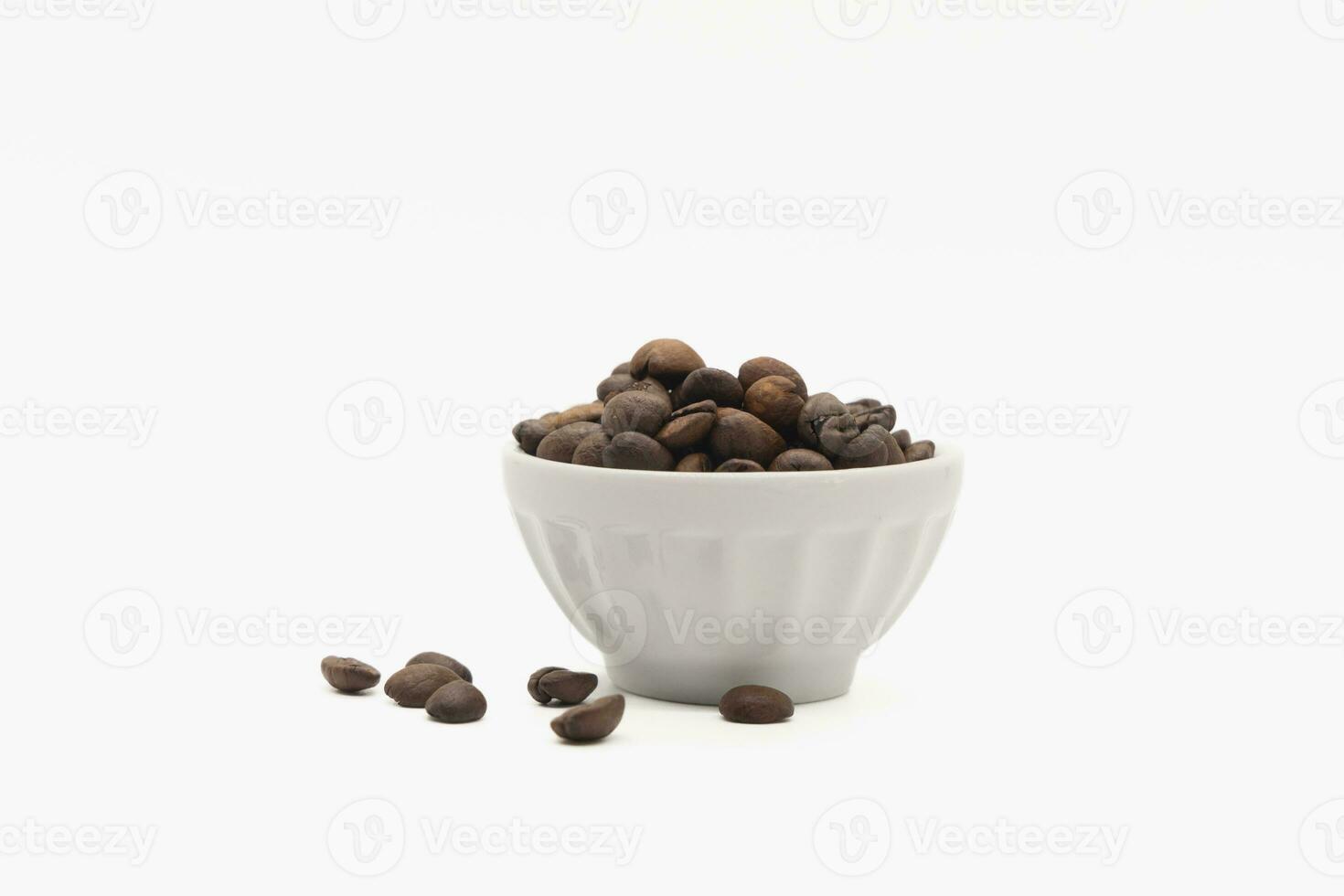 coffee beans in a white bowl and scattered on the isolated background photo