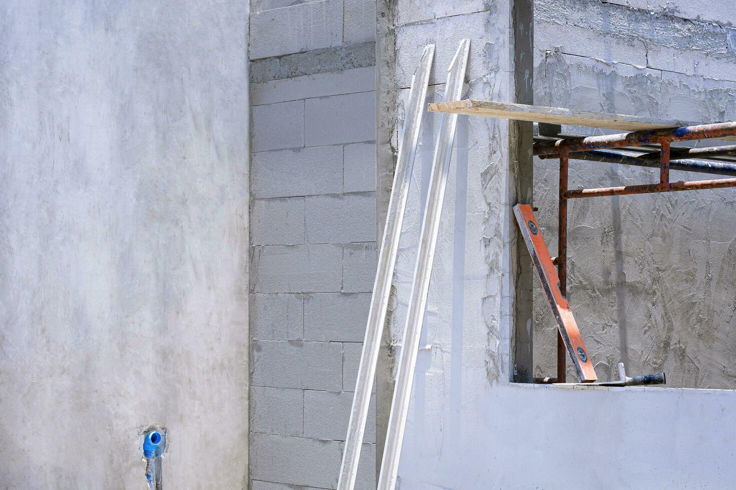 Perspective side view of 2 long wooden trowels with various work tools and scaffolding inside of window frame in house construction site area photo