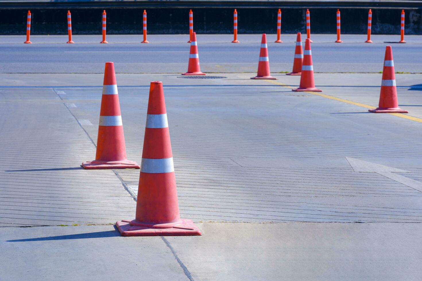 Orange traffic cones with plastic warning poles on entrance way that connect to main road for convenience and traffic safety in the city photo