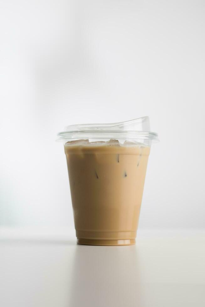 Iced cappuccino in a plastic glass on a white wooden table, minimalist-style picture. photo
