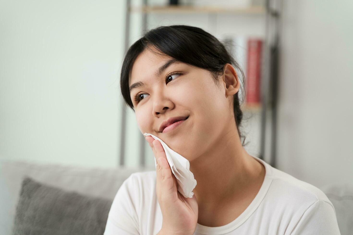 Young Asian woman wiping face with paper towel, Facial Cleansing Wipes, Removing Makeup. Beauty and fashion concept. photo