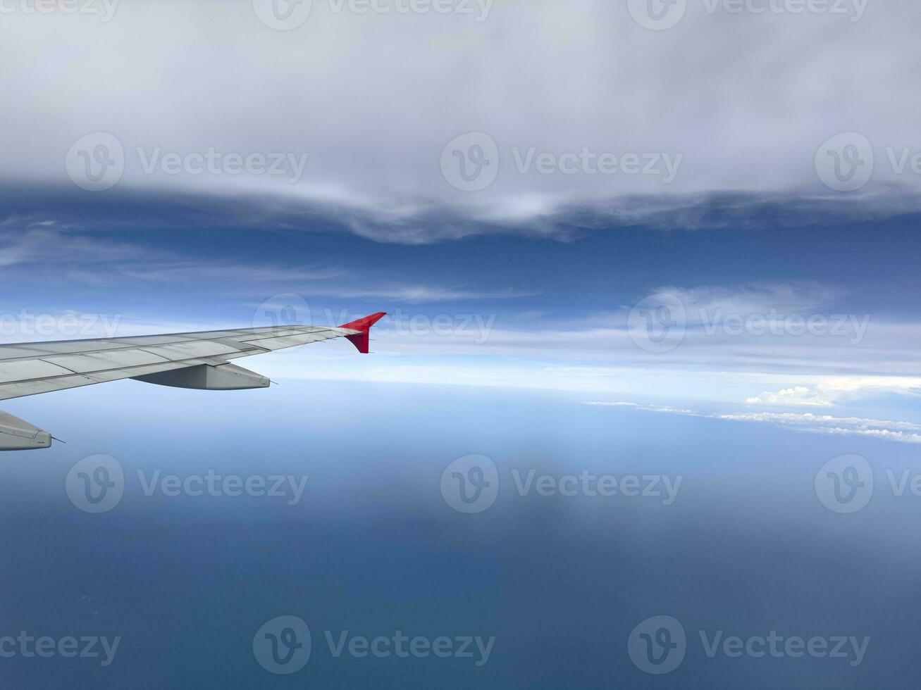 The wing of a modern airplane flying in the blue sky with few clouds during the journey. Copy space to insert text. photo