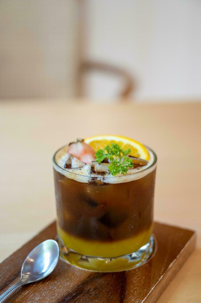 A glass of iced americano black coffee and layer of orange with sliced orange fruit photo