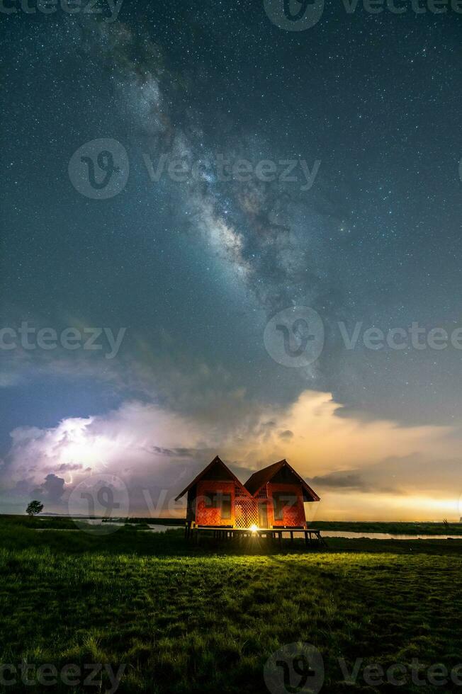 Milky way with twin house in grass field near thale noi, Phatthalung, Thailand photo