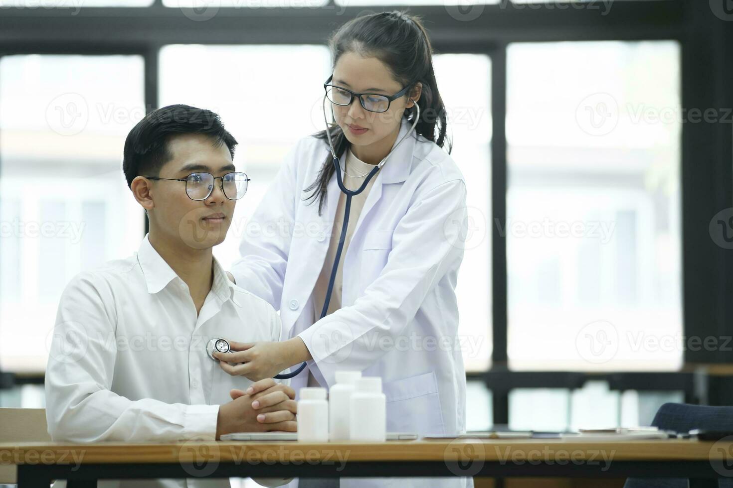 Young doctor is using a stethoscope listen to the heartbeat of the patient. photo