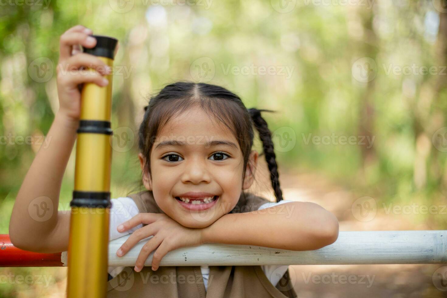 Asian little girls explore nature through magnifying glasses and binoculars in the park. Education, field trips, research, and discovery concepts. photo