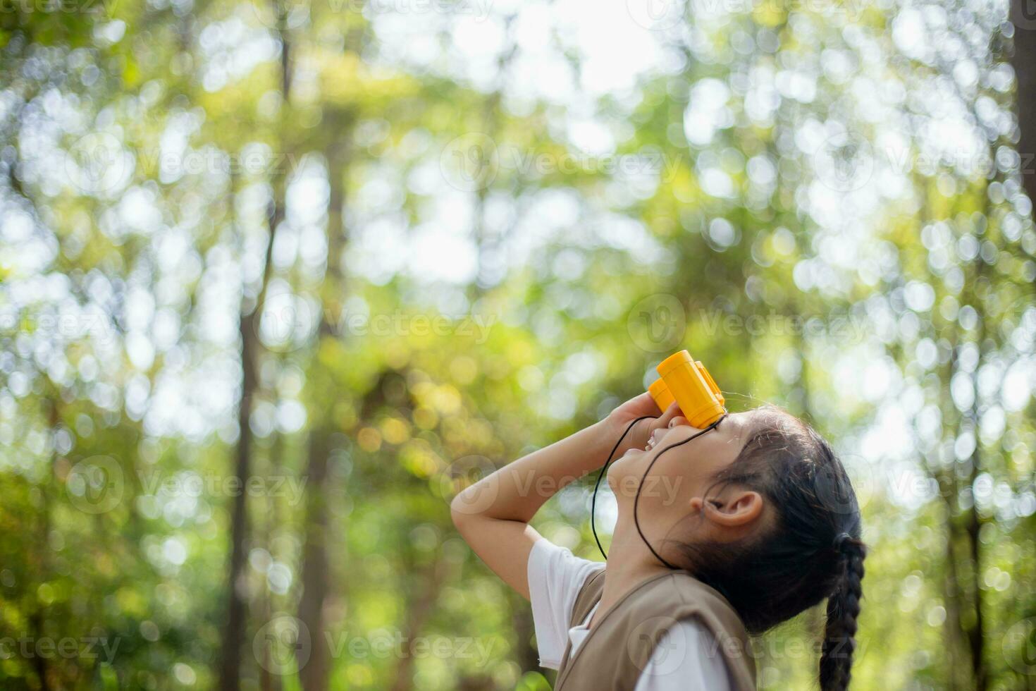 Happy Little Asian girls looking ahead and smiling child with the binoculars in the park. Travel and adventure concept. Freedom, vacation photo