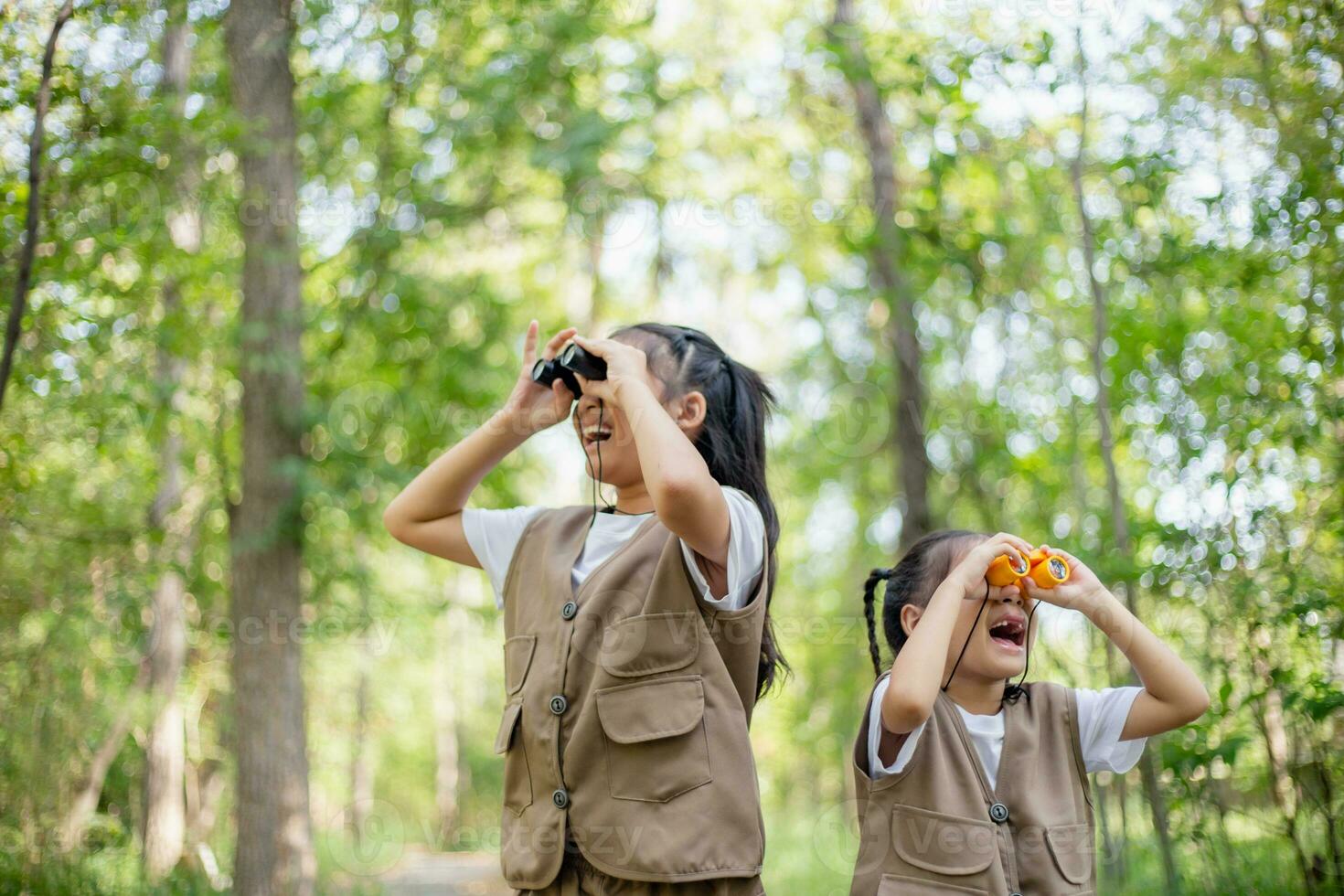 Happy Little Asian girls looking ahead and smiling child with the binoculars in the park. Travel and adventure concept. Freedom, vacation photo