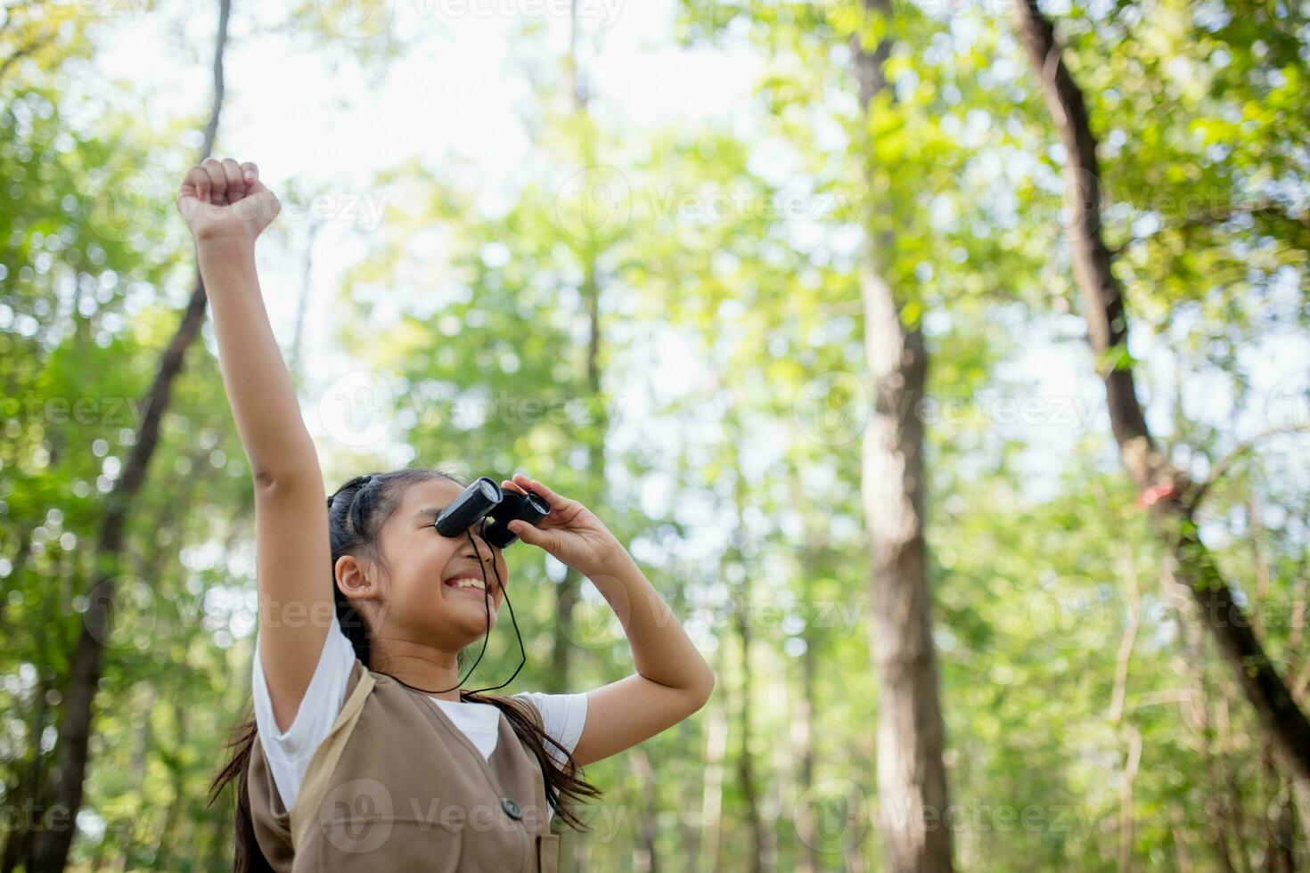 Happy Little Asian girls looking ahead and smiling child with the binoculars in the park. Travel and adventure concept. Freedom, vacation photo
