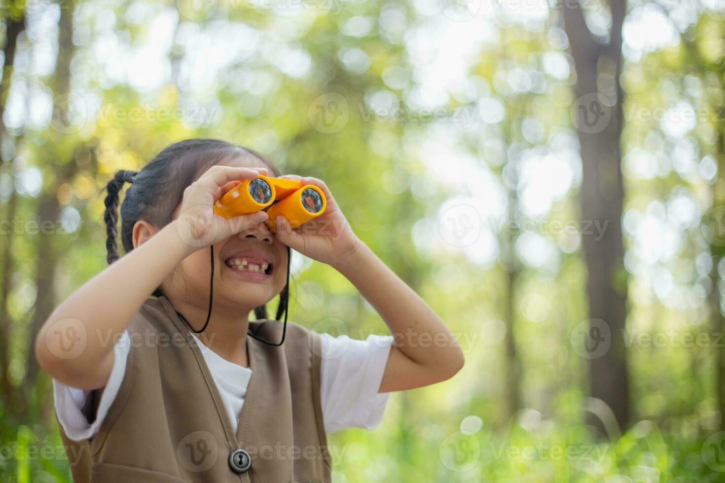 Happy Little Asian girls looking ahead and smiling child with the binoculars in the park. Travel and adventure concept. Freedom, vacation photo