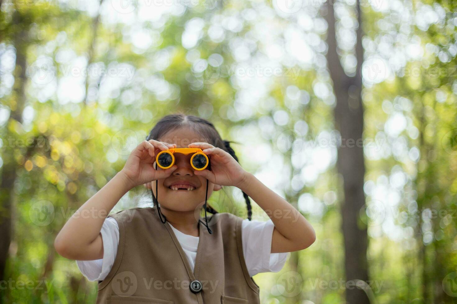 Happy Little Asian girls looking ahead and smiling child with the binoculars in the park. Travel and adventure concept. Freedom, vacation photo