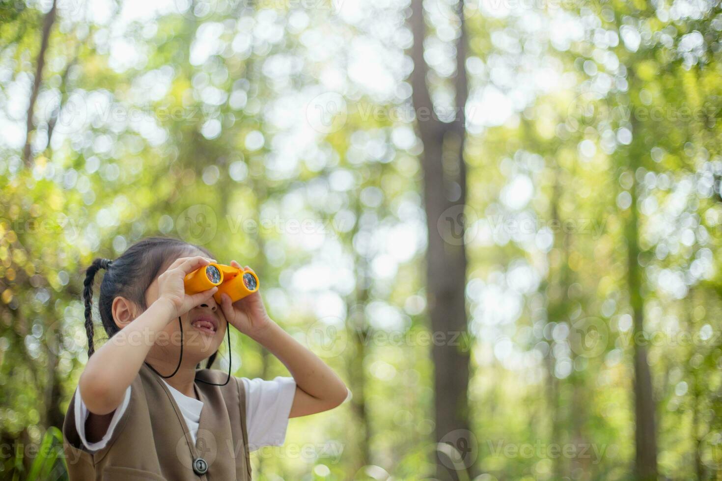 Happy Little Asian girls looking ahead and smiling child with the binoculars in the park. Travel and adventure concept. Freedom, vacation photo