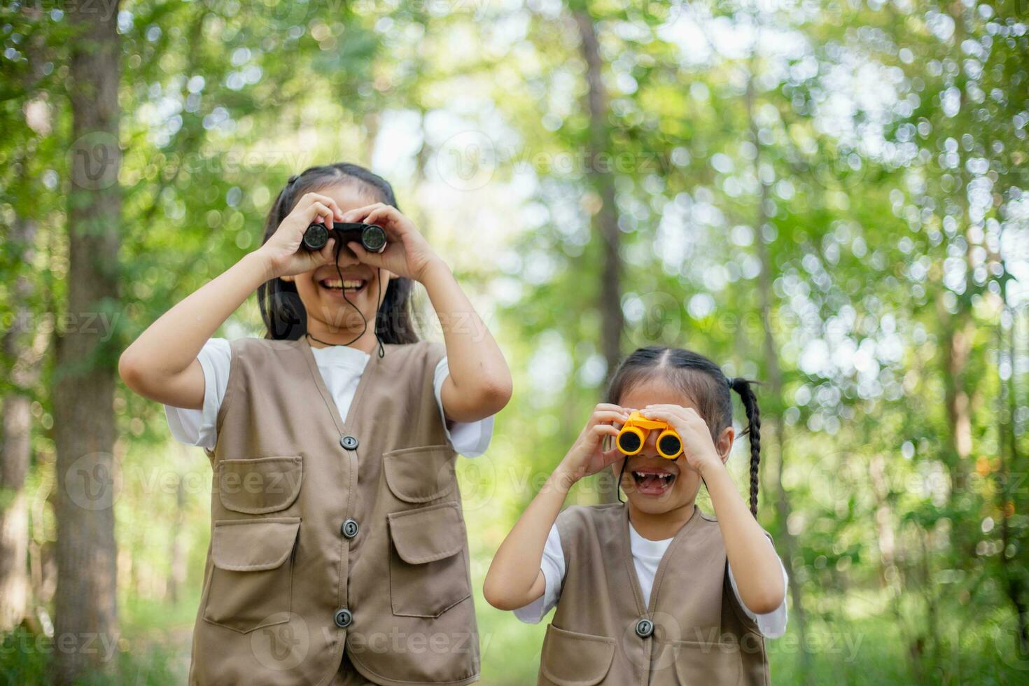 Happy Little Asian girls looking ahead and smiling child with the binoculars in the park. Travel and adventure concept. Freedom, vacation photo