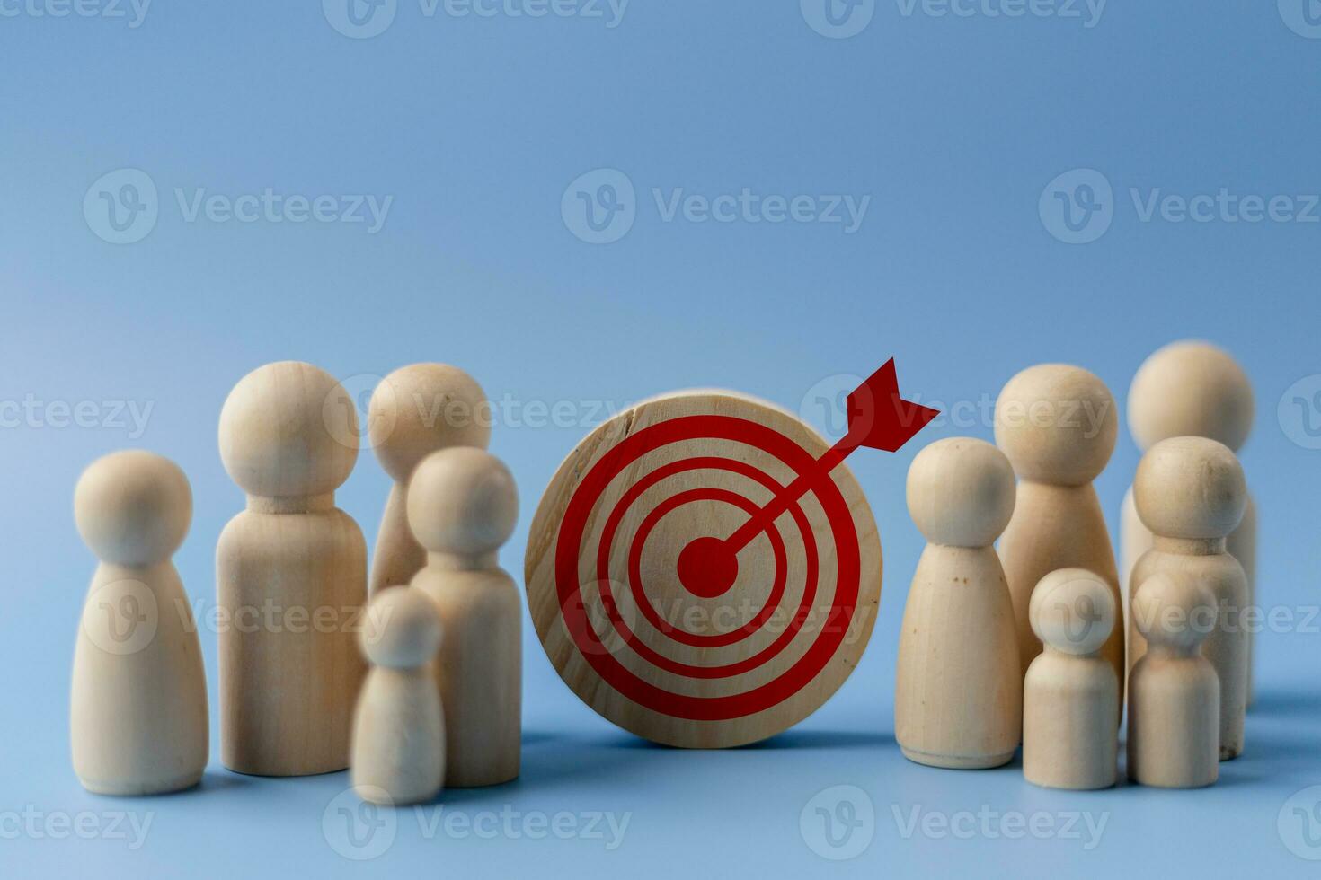 Business target concept. Wooden figures of people and a target on a blue background. photo