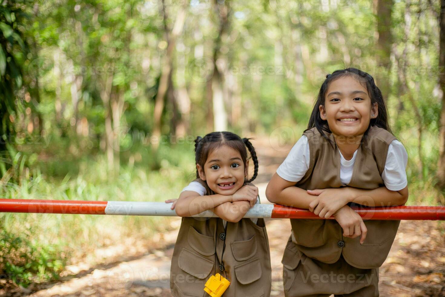 Asian little girls explore nature through magnifying glasses and binoculars in the park. Education, field trips, research, and discovery concepts. photo