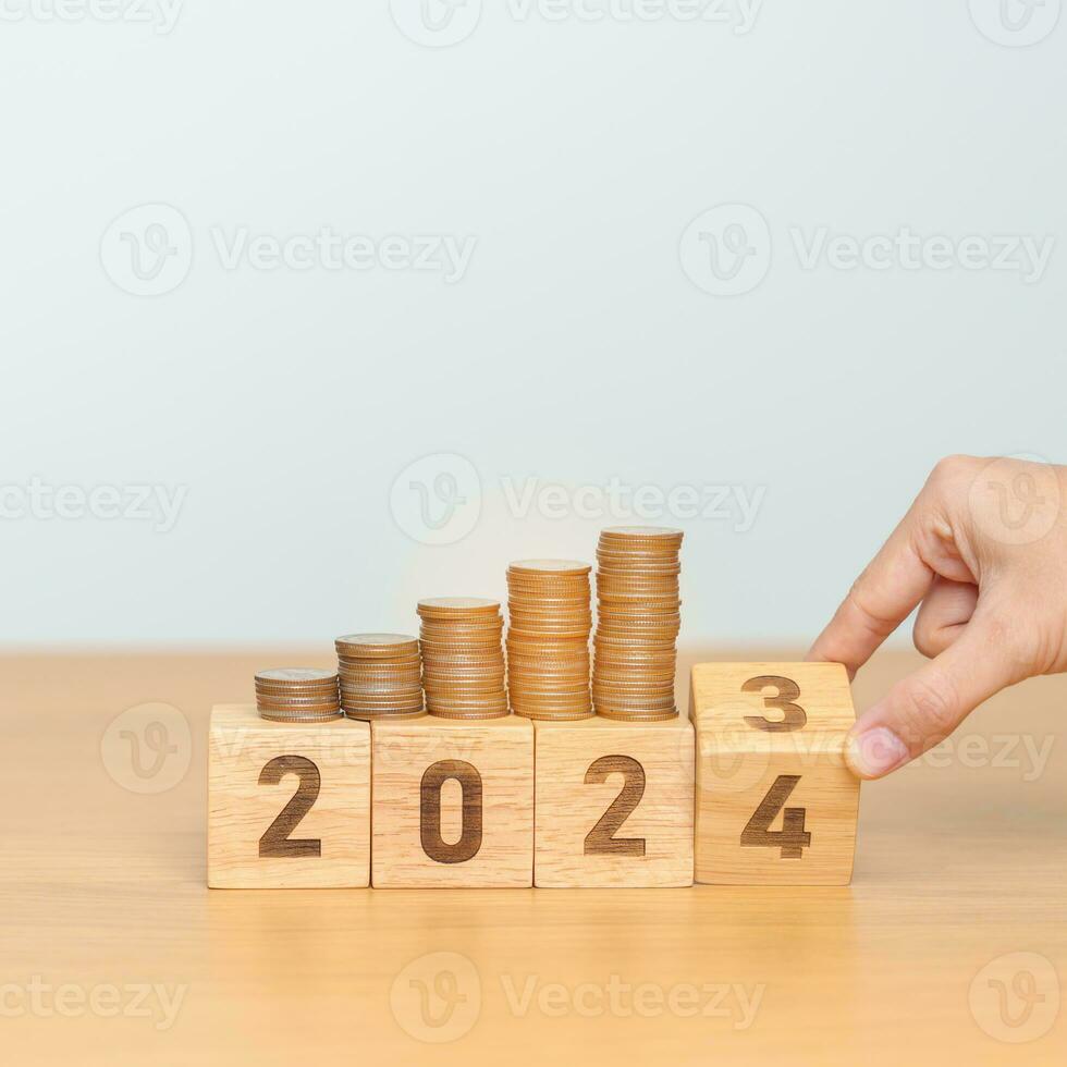 flipping 2023 to 2024 year block with Coins stack. Money, Budget, tax, investment, financial, savings and New Year Resolution concepts photo