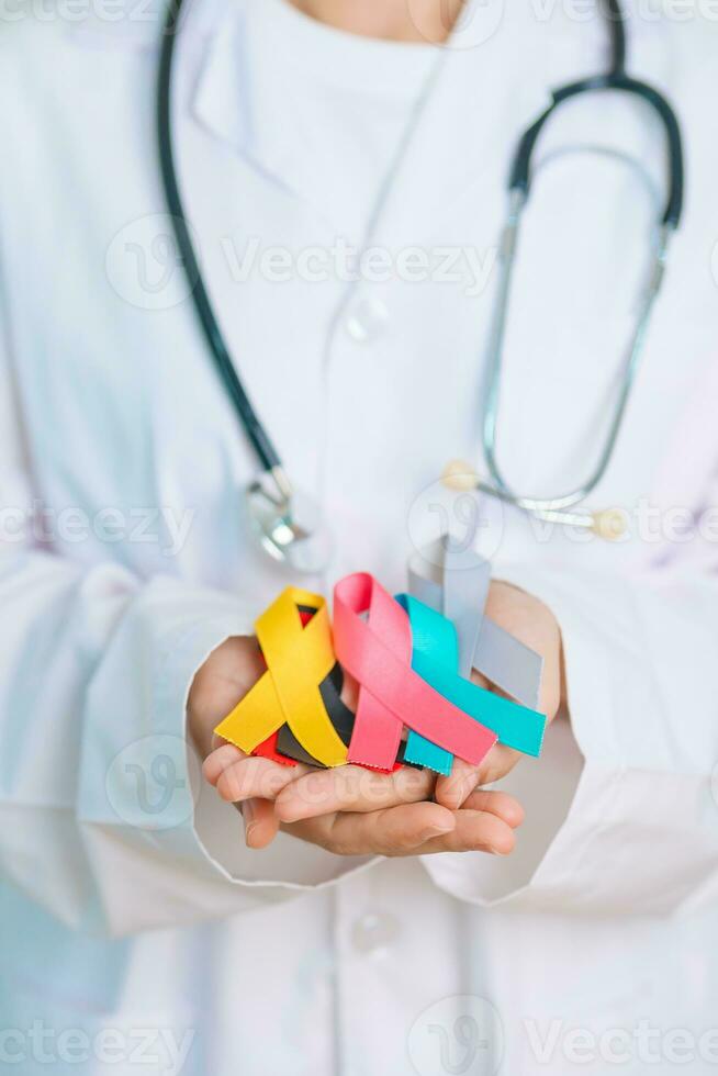 World cancer day, February 4. Doctor hold colorful ribbons, blue, yellow, red, green, white, pink and grey for supporting people living and illness. Health, Medical, awareness and Insurance concept photo