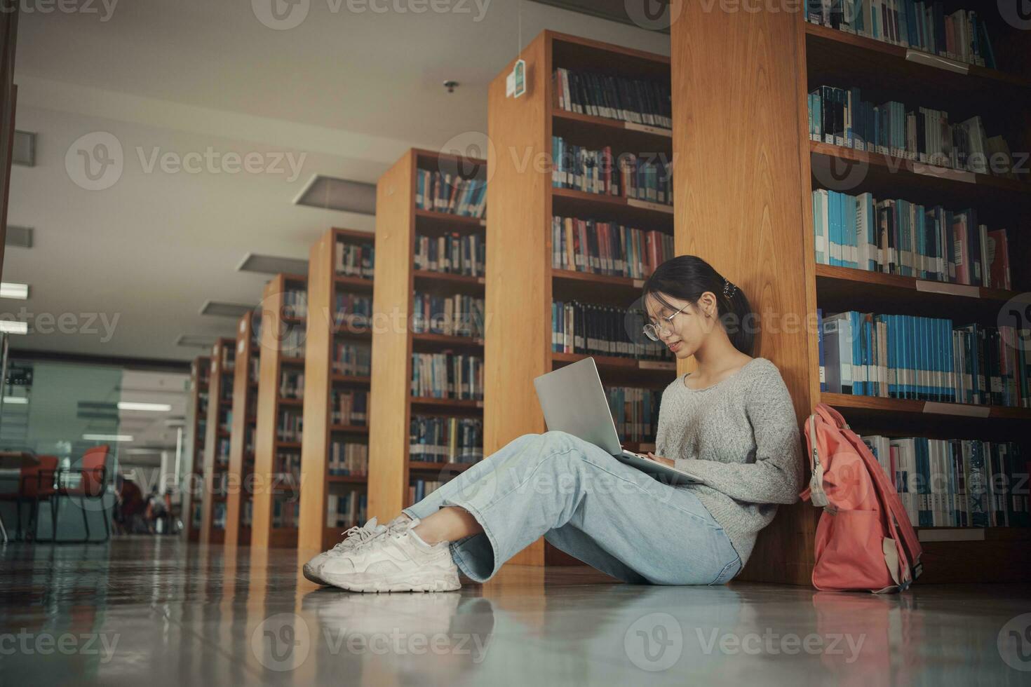 Student girl sitting on floor and using laptop, Writes notes for paper, Essay, Study for class assignment. Diverse group of Students Learning, Studying for Exams. photo