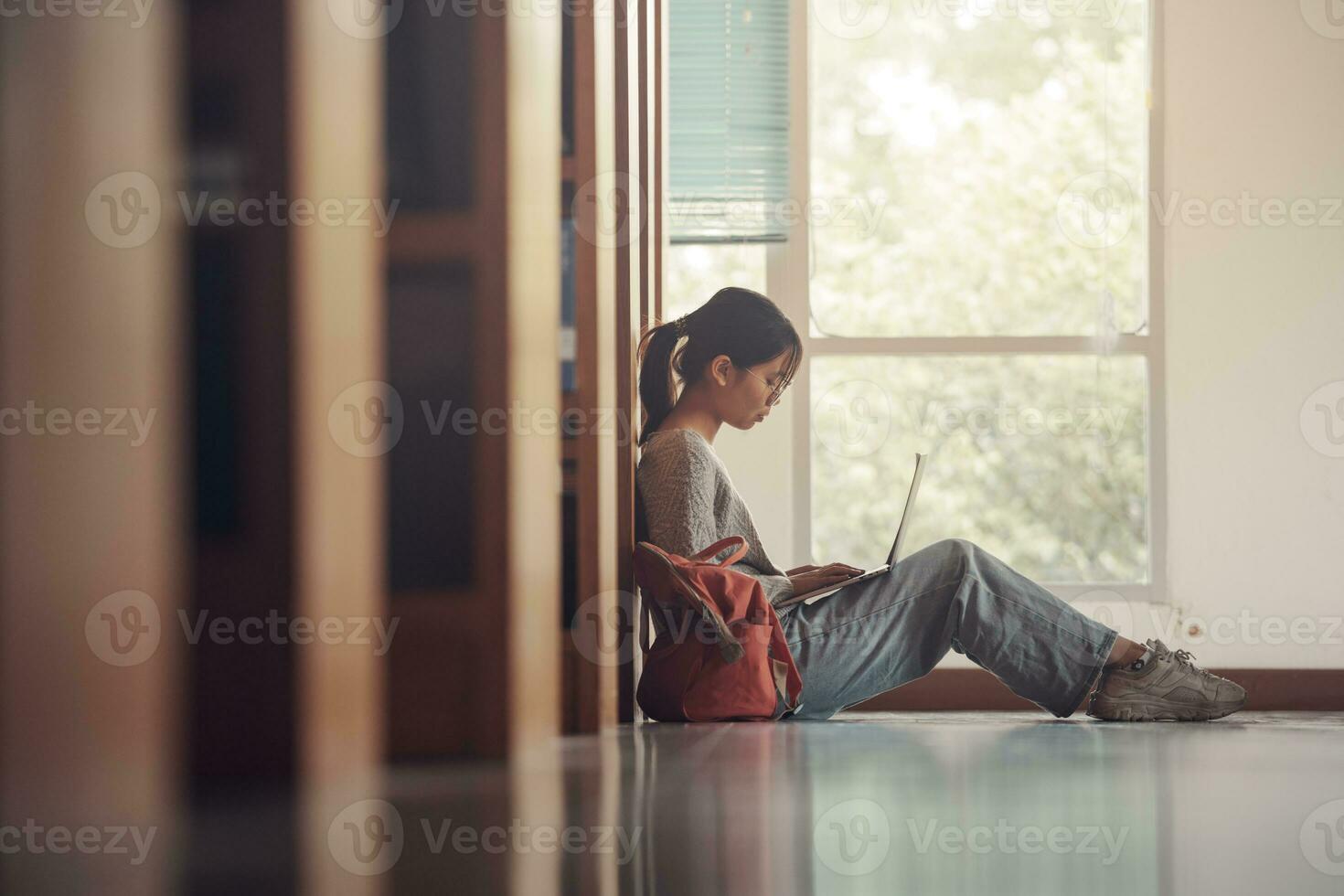 Student girl sitting on floor and using laptop, Writes notes for paper, Essay, Study for class assignment. Diverse group of Students Learning, Studying for Exams. photo