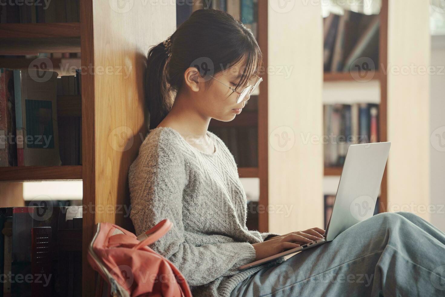 Student girl sitting on floor and using laptop, Writes notes for paper, Essay, Study for class assignment. Diverse group of Students Learning, Studying for Exams. photo