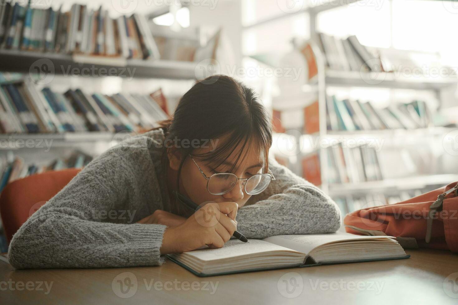 aburrido estudiante niña acostado en libro y leyendo libro, estudiante niña a aburrido lección sensación cansado o deprimido. foto