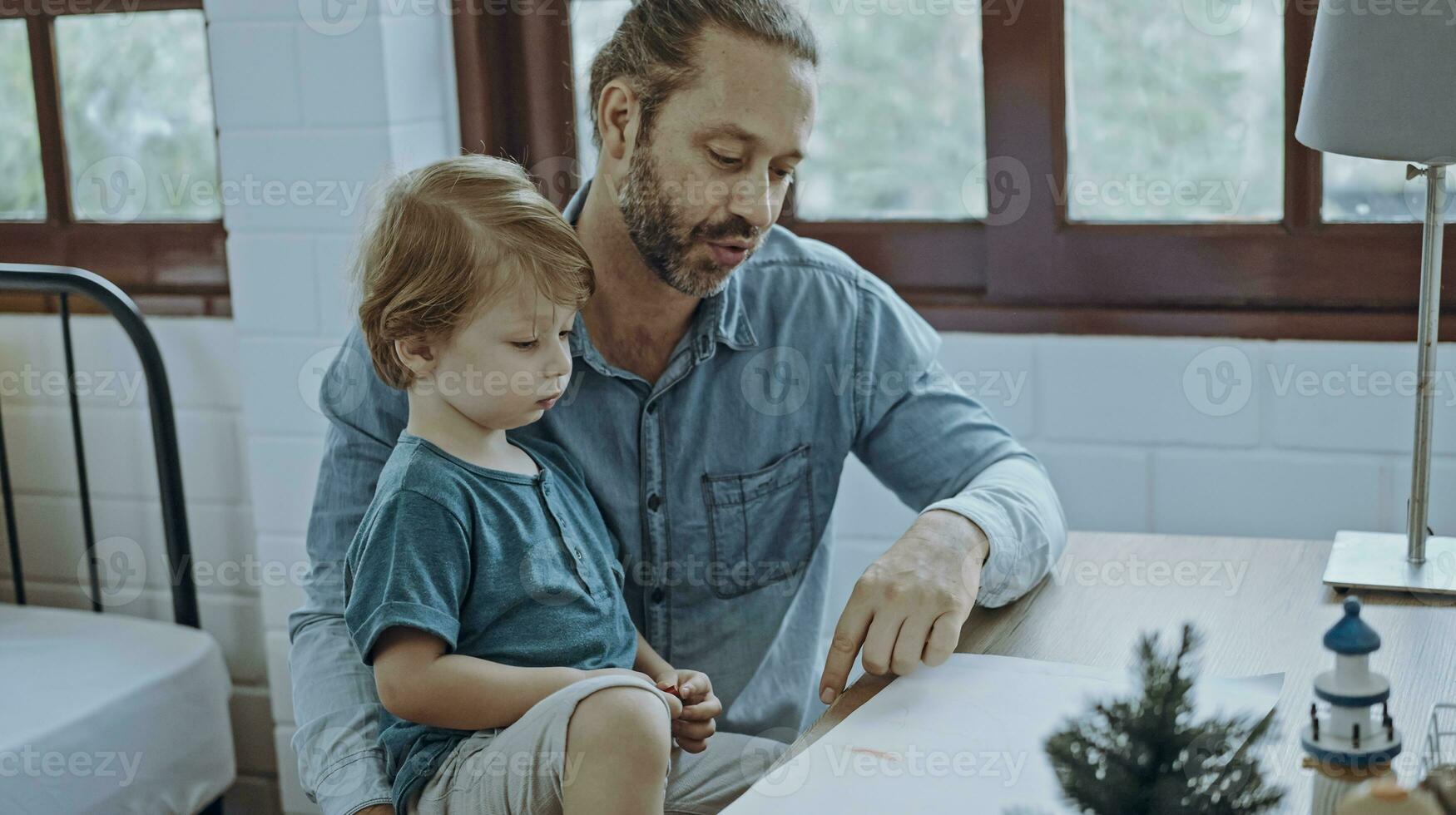 Caucasian family painting on paper with son indoors in house. Little son learn how to draw art picture enjoy creativity with father in house. photo