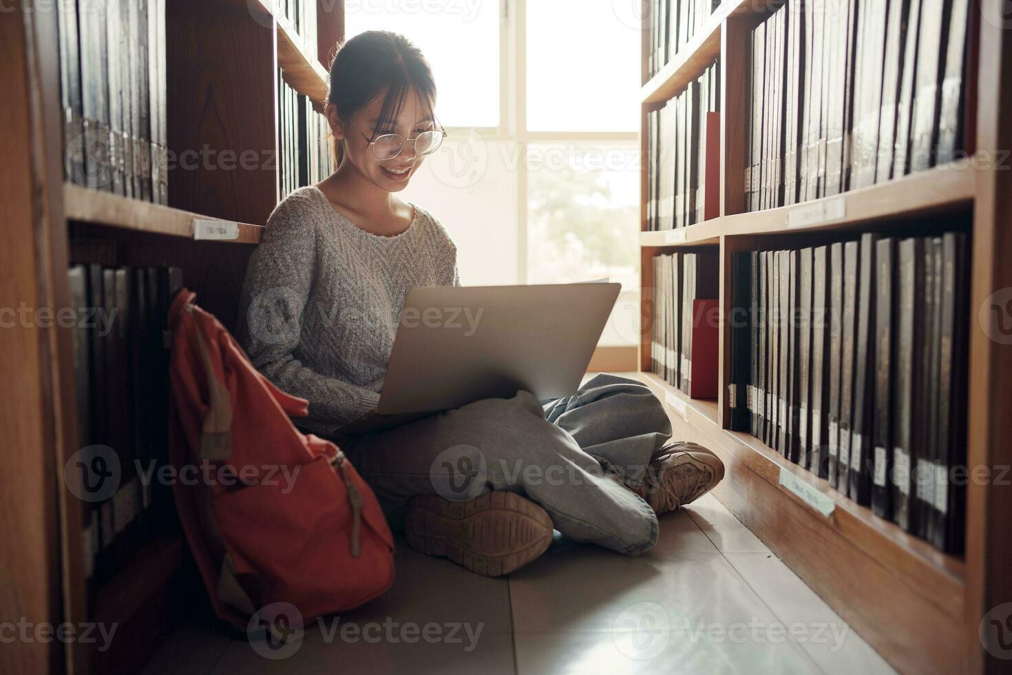 Student girl sitting on floor and using laptop, Writes notes for paper, Essay, Study for class assignment. Diverse group of Students Learning, Studying for Exams. photo