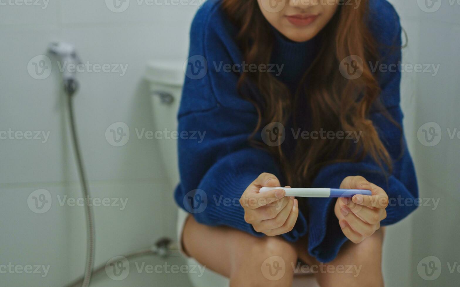 Unstressed woman sitting on toilet and waiting for pregnancy test
