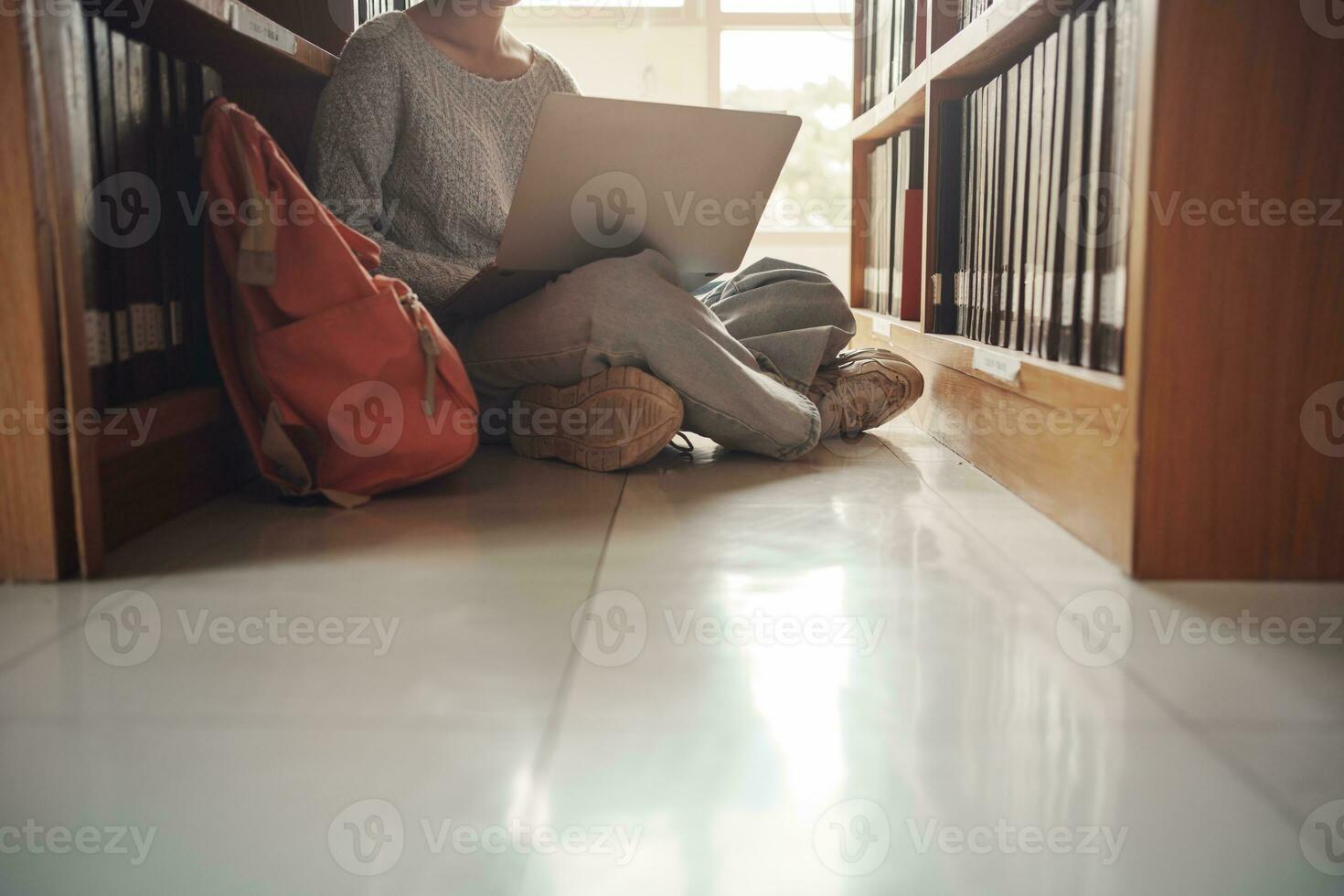 Student girl sitting on floor and using laptop, Writes notes for paper, Essay, Study for class assignment. Diverse group of Students Learning, Studying for Exams. photo