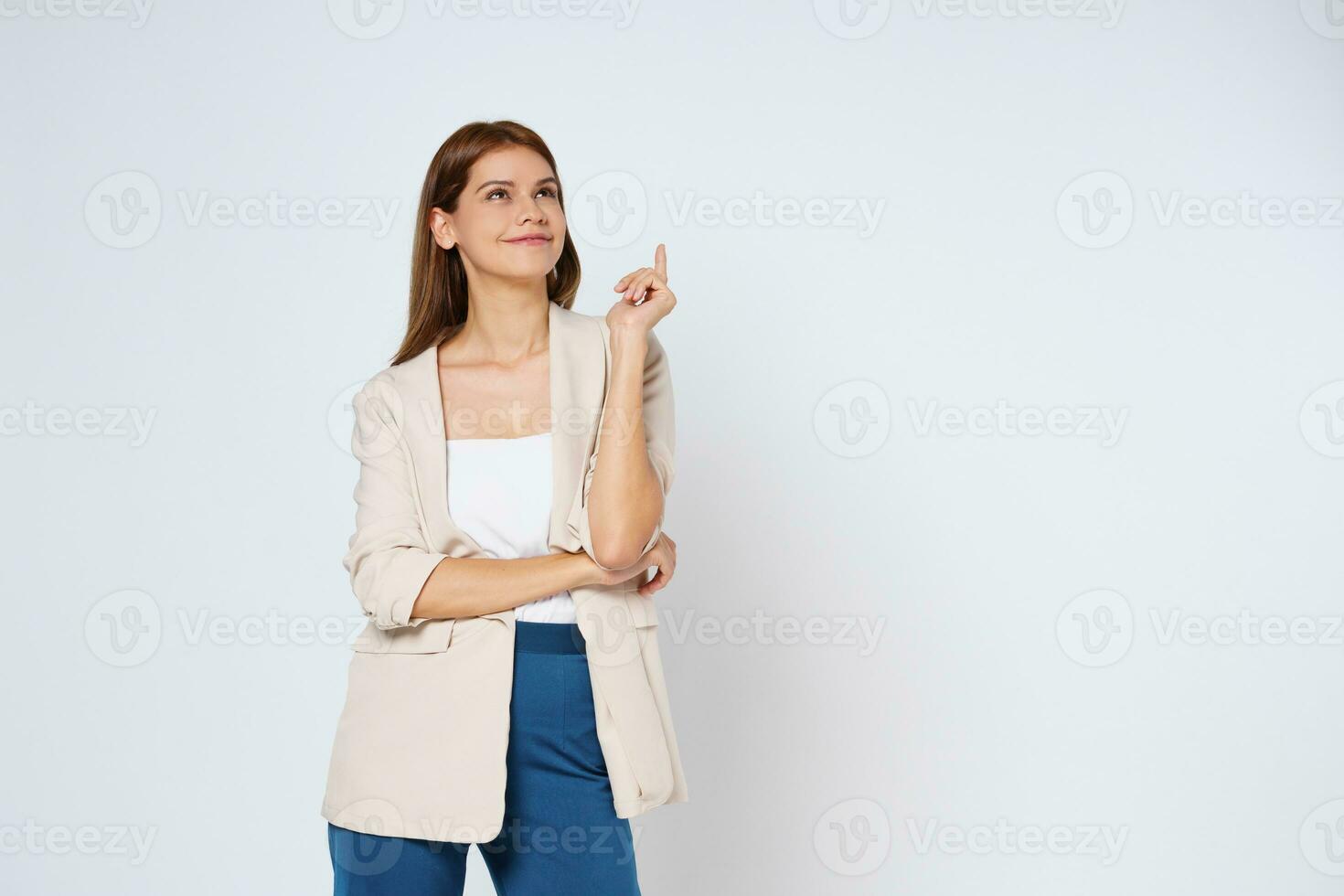 Young woman smiling and pointing finger to empty copy space isolated on white background. photo