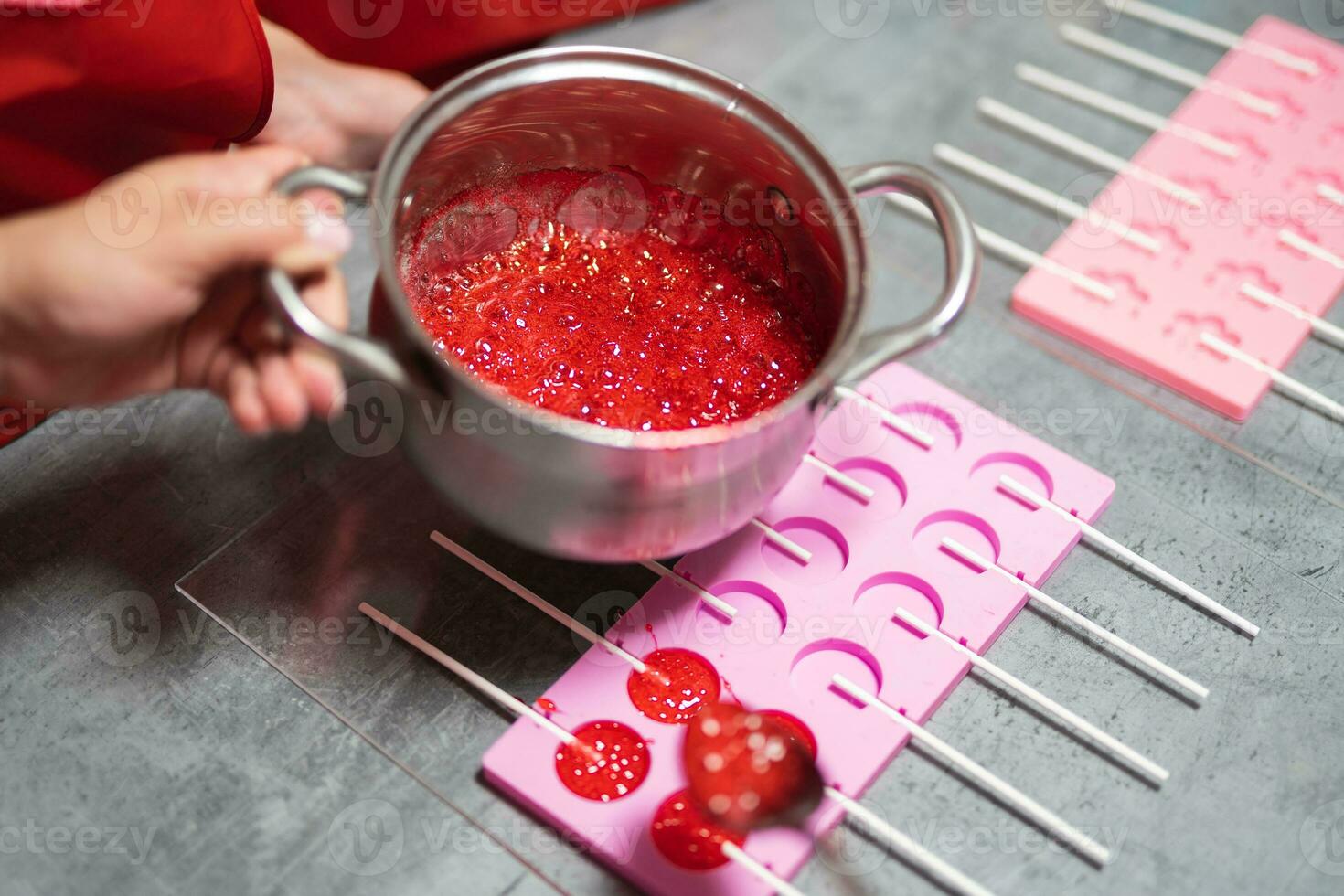 process of making delicious lollipops by pouring them into molds photo