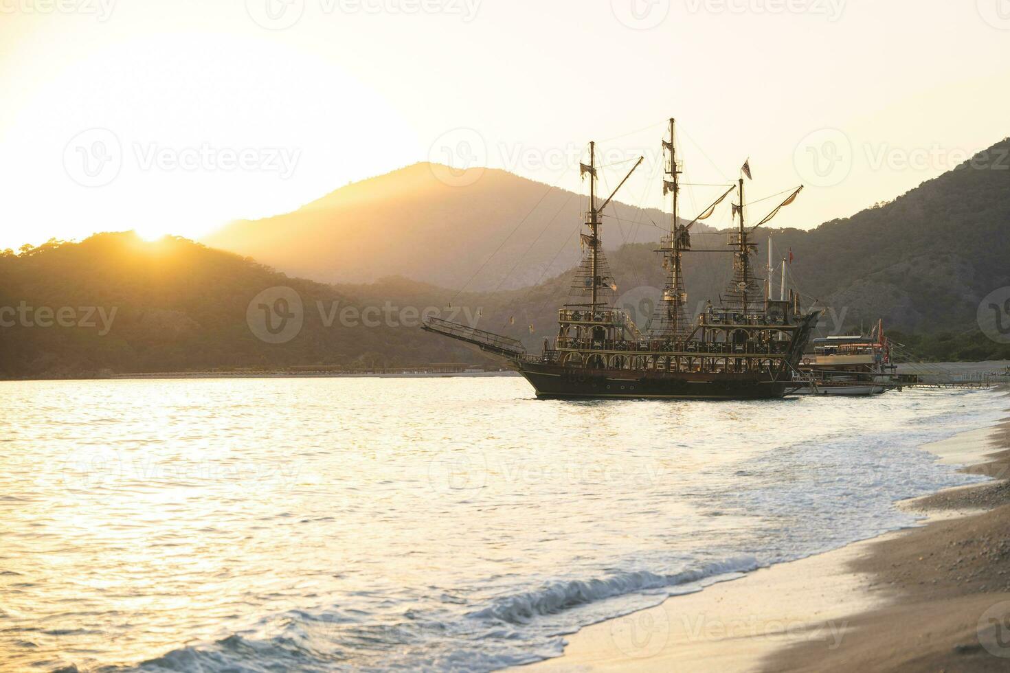 a large ship is docked at the seashore at sunset and beautiful mountains photo