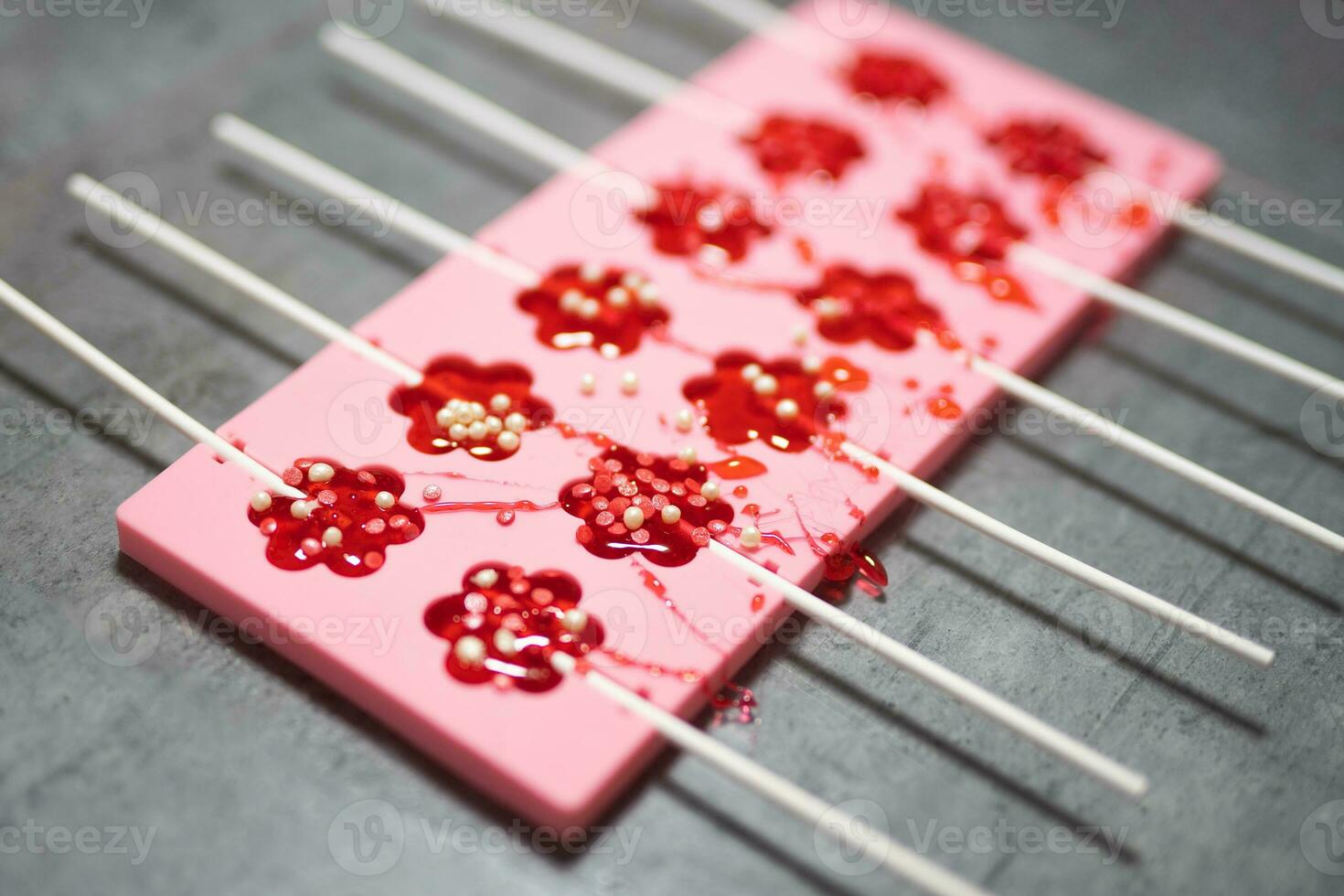 process of making delicious lollipops by pouring them into molds photo