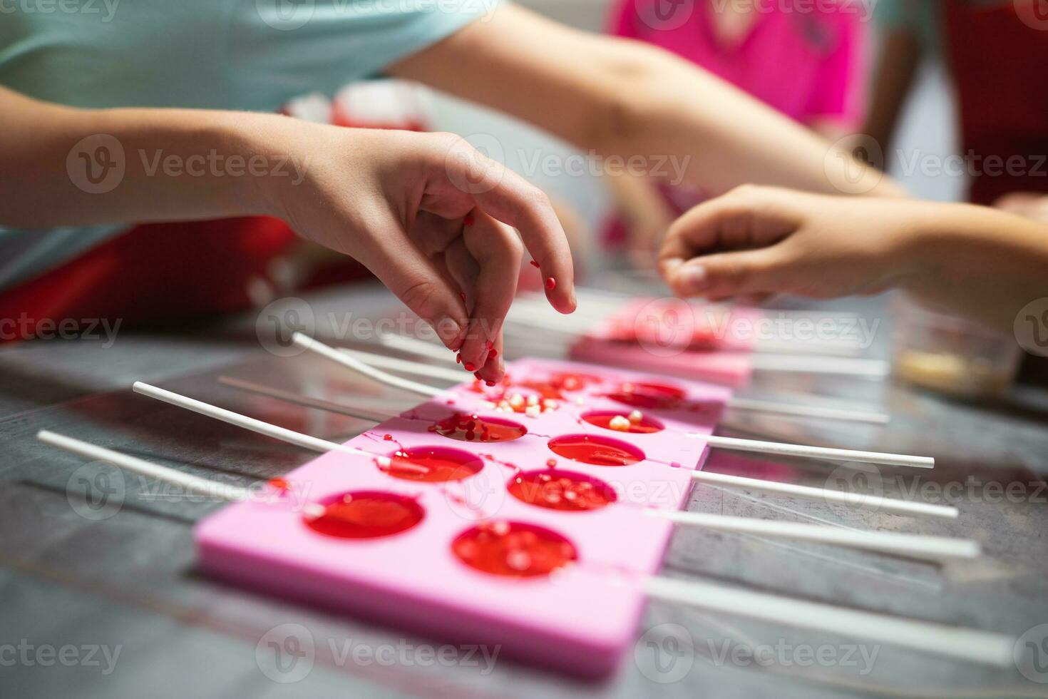 process of making delicious lollipops by pouring them into molds photo