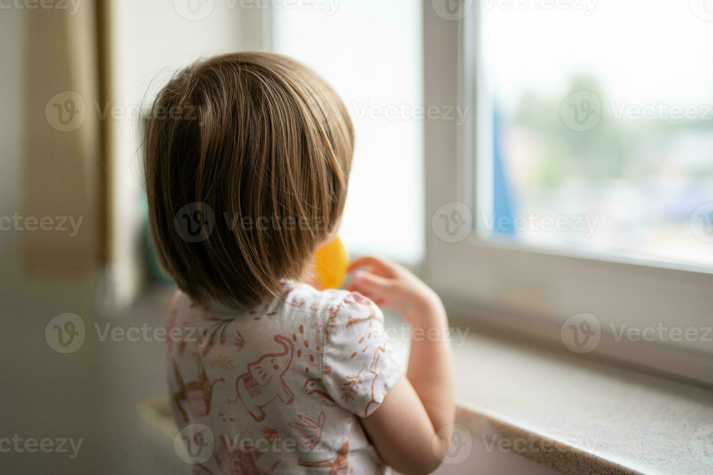 a small child looks out the window from behind photo