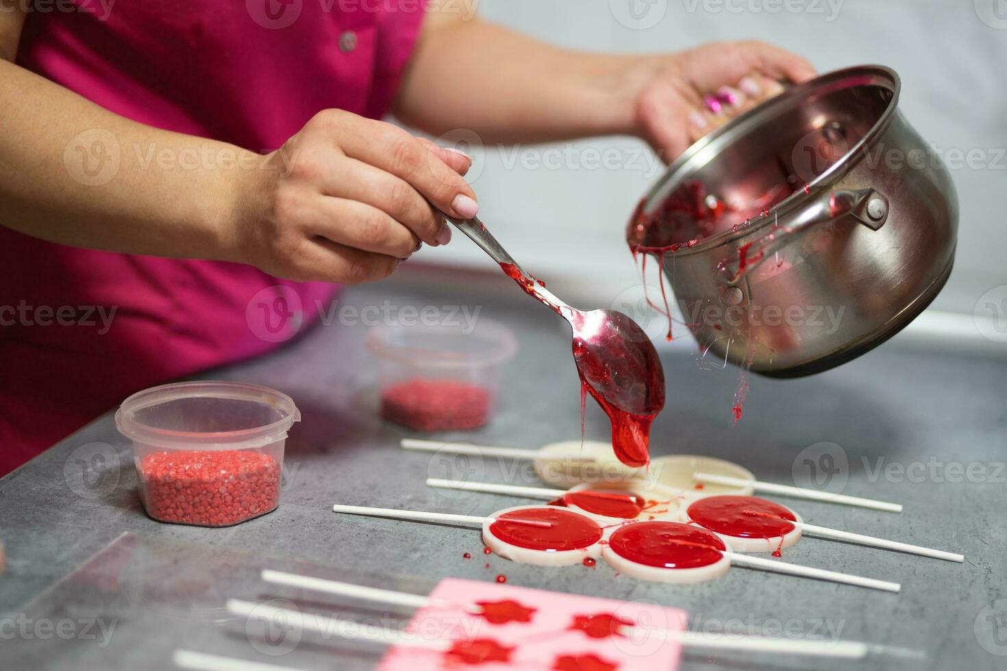 process of making delicious lollipops by pouring them into molds photo