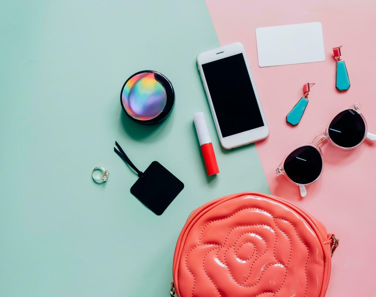 Flat lay of pink cute woman bag open out with cosmetics, accessories, tag card and smartphone on colorful background with copy space photo