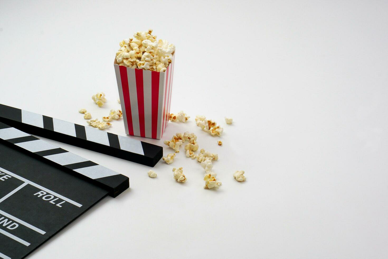 Clapperboard or movie slate black color with popcorn on white background. Cinema industry, video production and film concept. photo