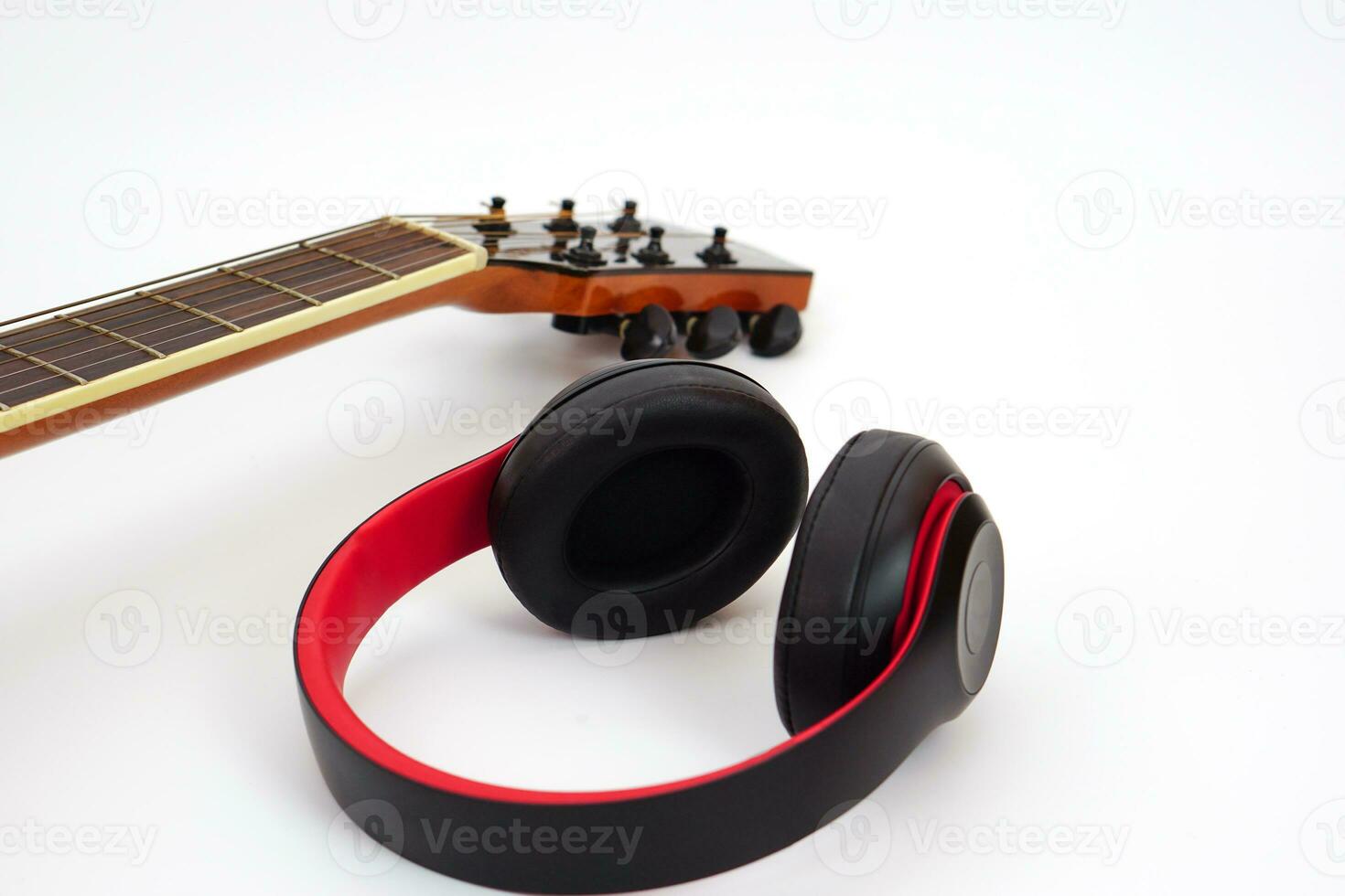 Selective focus, Acoustic guitar neck on a white background and the headphones are placed on the side. Concept of love, leisure and music. photo