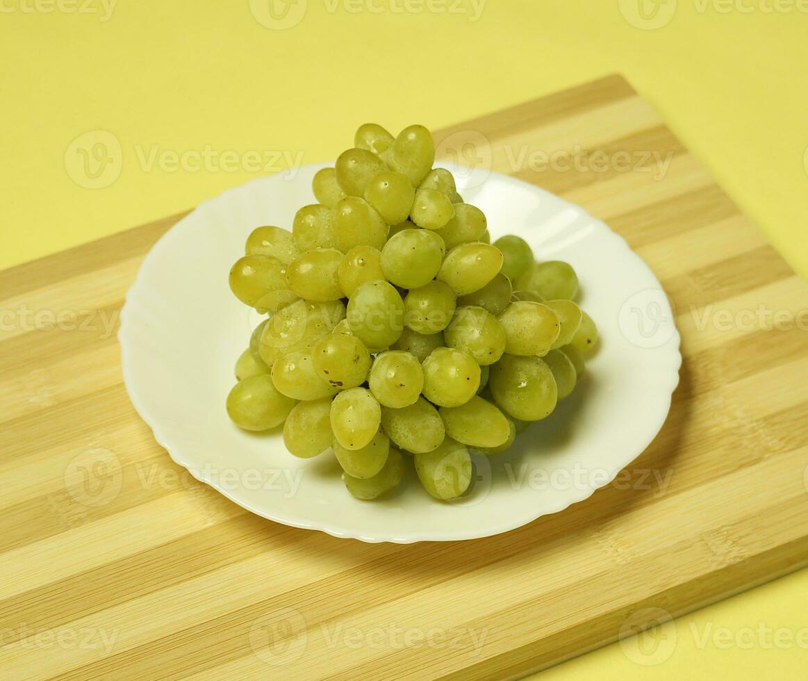 A plate of grapes on a wooden board photo