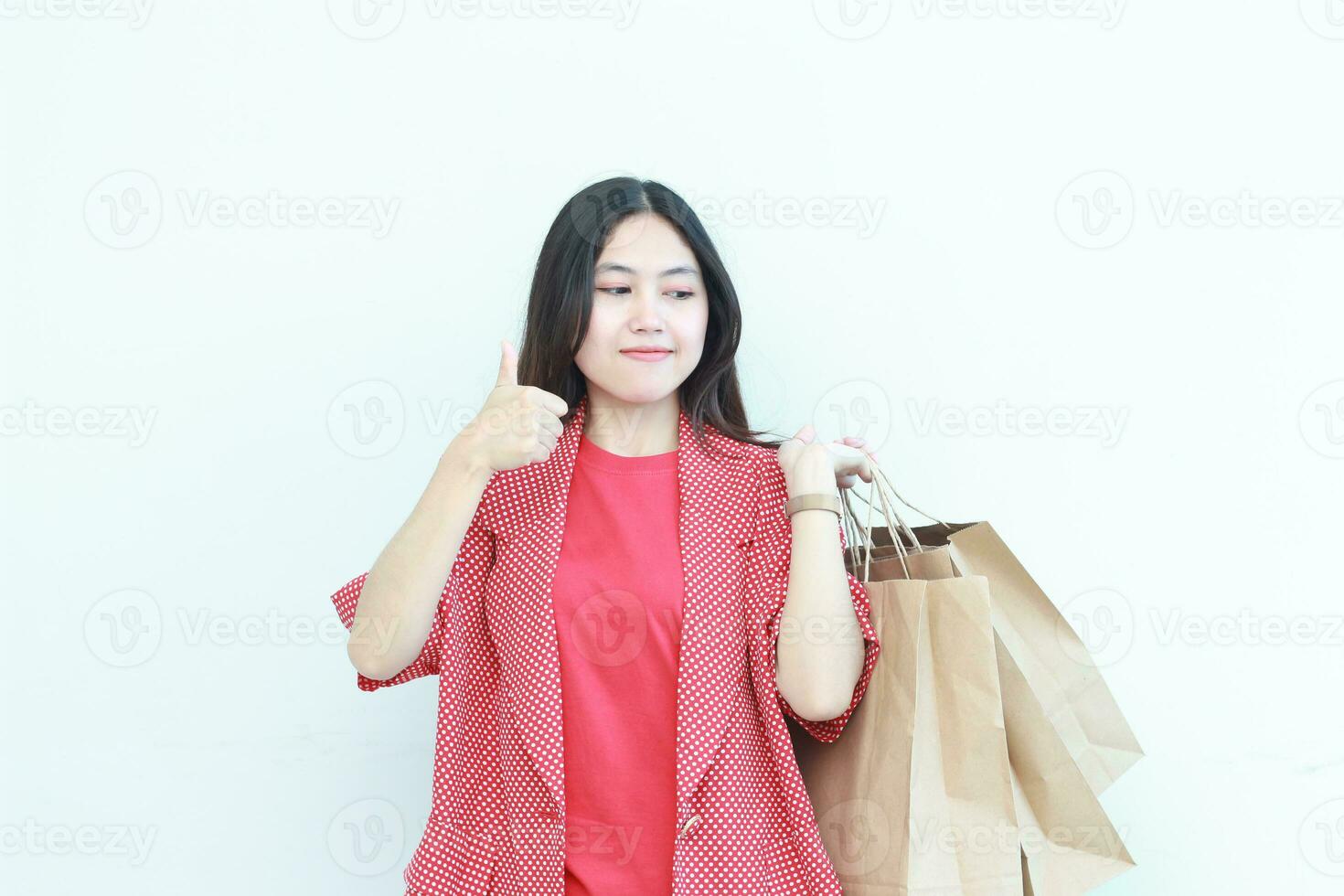 retrato de hermosa asiático mujer vistiendo rojo atuendo gesticulando que lleva un montón de compras pantalones con contento expresión foto