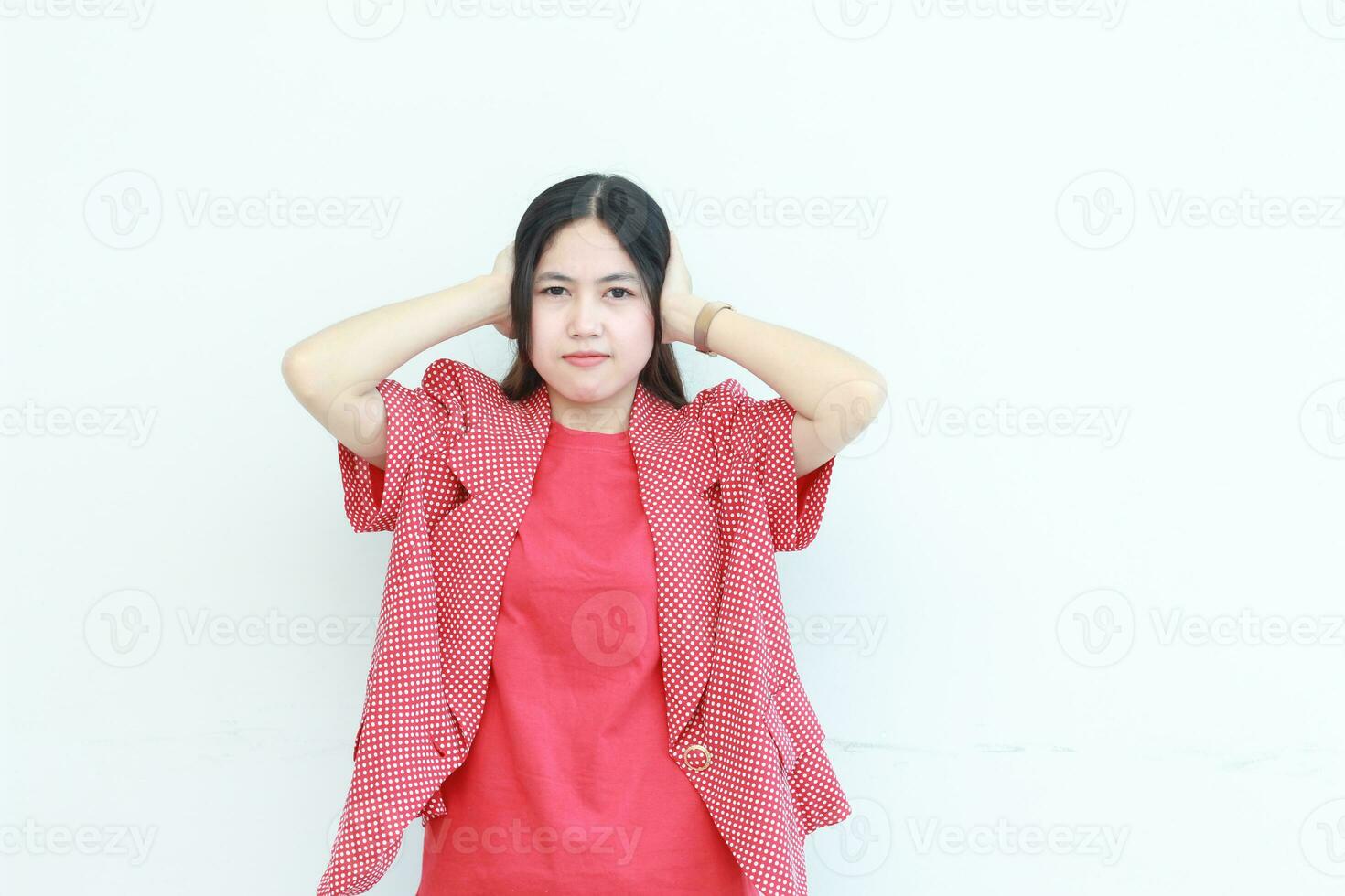 portrait of beautiful asian woman wearing red outfit gesturing to cover ears because of noise photo