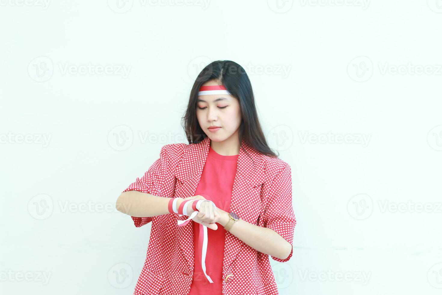 portrait of an asian woman wearing a red outfit tying her hands with a flag ribbon in the context of independence day of Indonesia photo