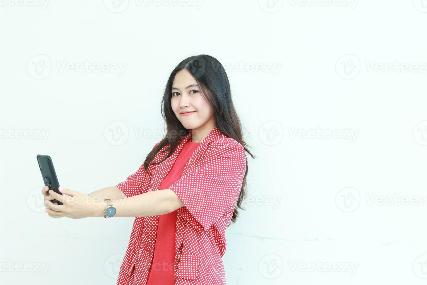 portrait of beautiful asian woman wearing red outfit holding mobile phone and smiling photo