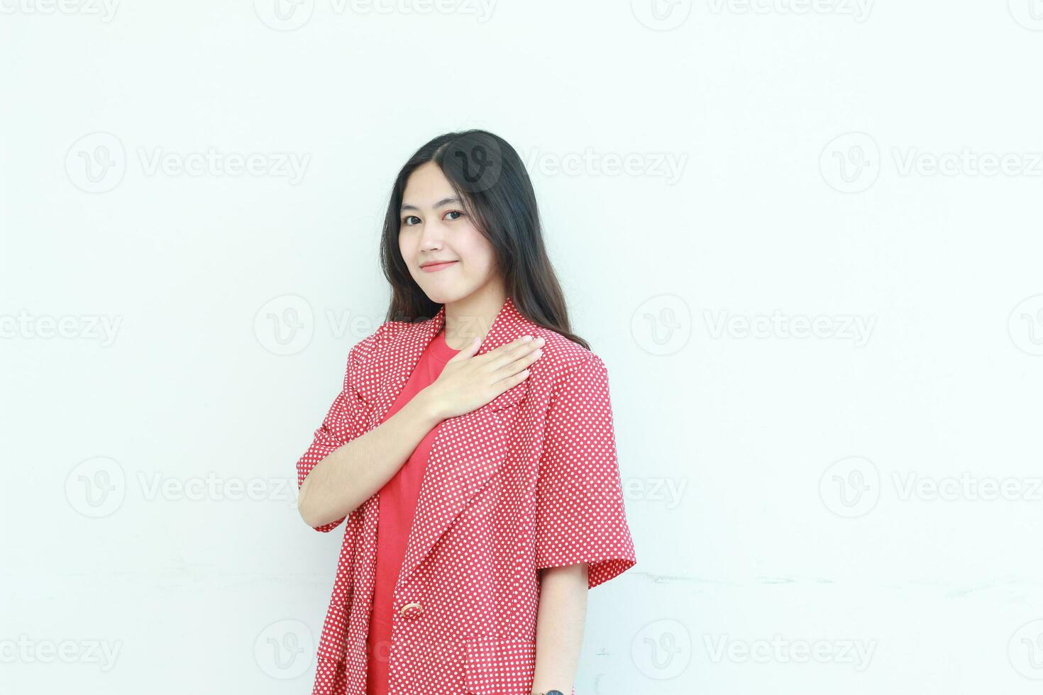 portrait of beautiful asian woman wearing red outfit with hand gesturing on chest while smiling photo