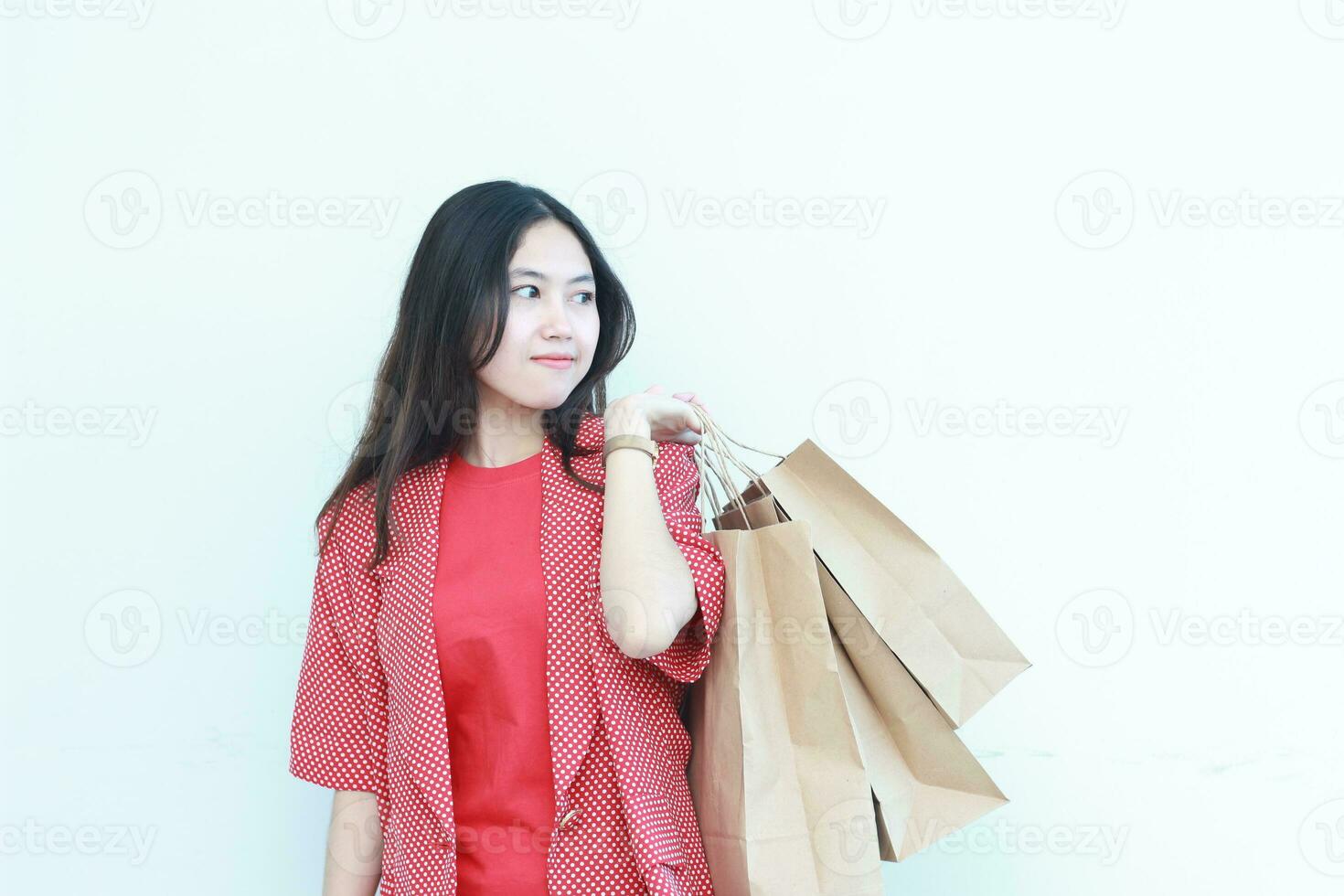 portrait of beautiful asian woman wearing red outfit gesturing carrying lots of shopping bags with happy expression photo