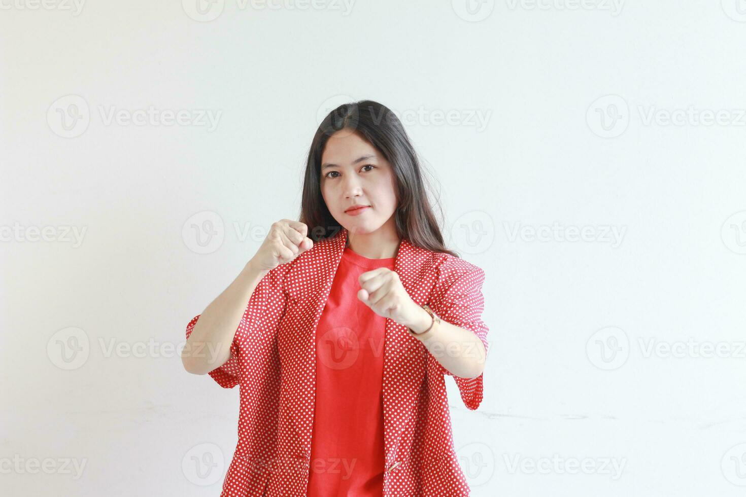 portrait of beautiful asian woman wearing red outfit with fist gesturing with serious expression photo