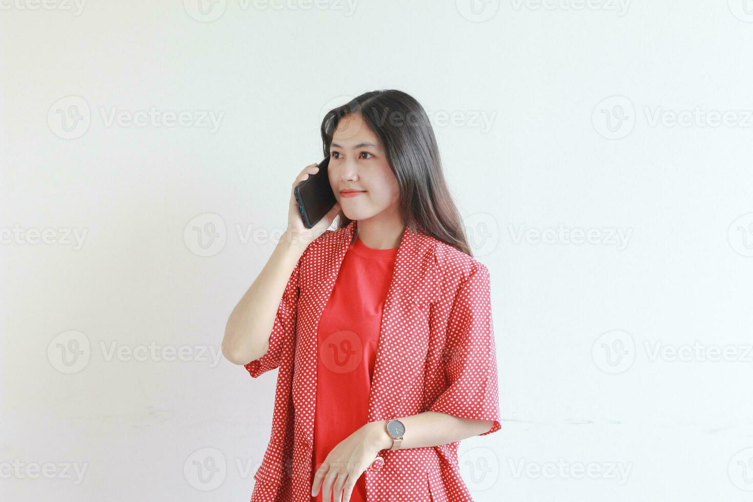 portrait of beautiful asian woman wearing red outfit while calling with smiling expression photo